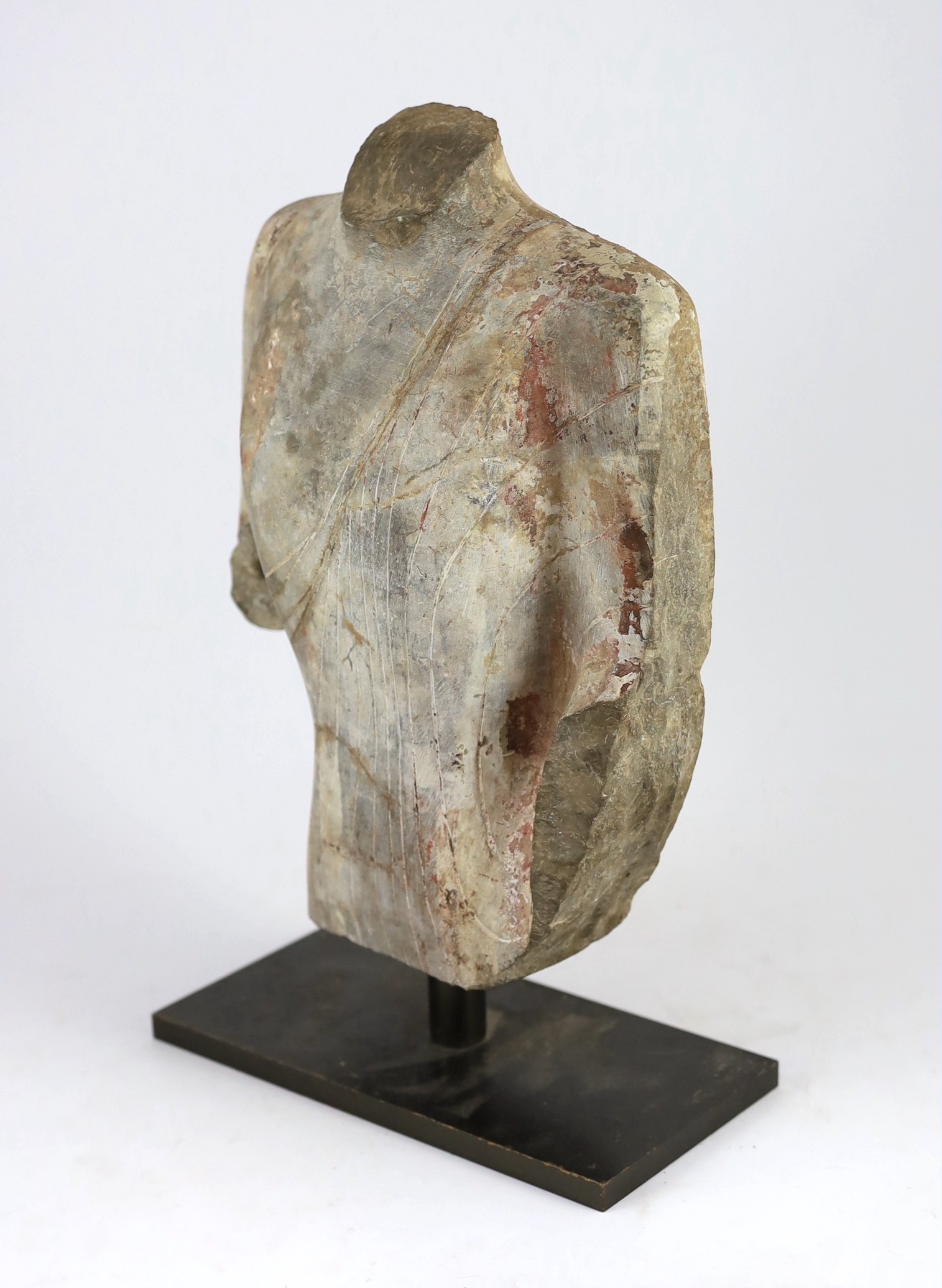A Chinese pigment painted limestone torso of Buddha, probably Northern Qi dynasty (550-577 CE), 36cm high, mounted on a later base, total height 42.5cm